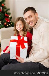 christmas, x-mas, winter, happiness and people concept - smiling father and daughter holding gift box