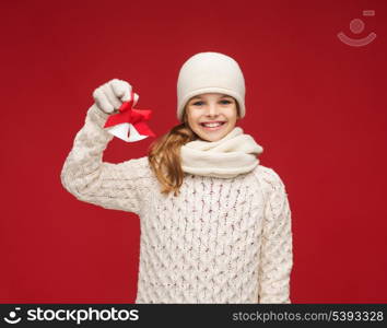 christmas, x-mas, winter, happiness concept - smiling girl in hat, muffler and gloves with jingle bells