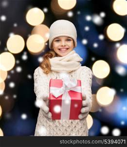 christmas, x-mas, winter, happiness concept - smiling girl in hat, muffler and gloves with gift box