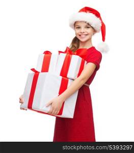christmas, x-mas, winter, happiness concept - smiling girl in santa helper hat with many gift boxes
