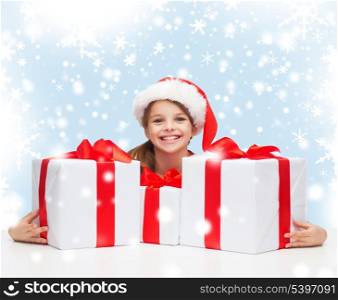 christmas, x-mas, winter, happiness concept - smiling girl in santa helper hat with many gift boxes
