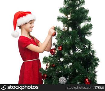 christmas, x-mas, winter, happiness concept - smiling girl in santa helper hat decorating a tree