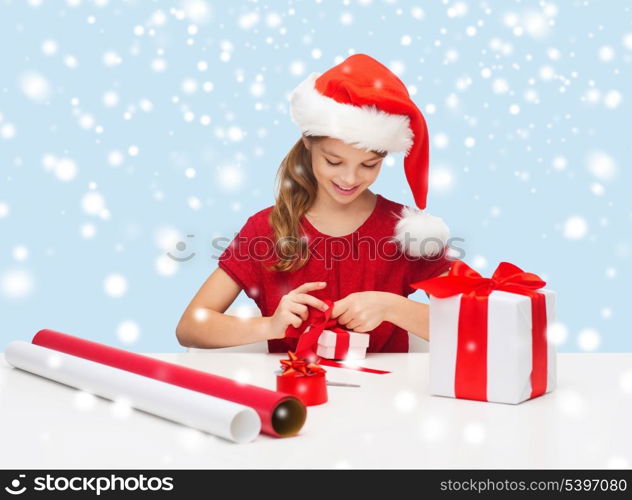 christmas, x-mas, winter, happiness concept - smiling girl in santa helper hat with gift box