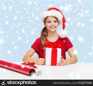 christmas, x-mas, winter, happiness concept - smiling girl in santa helper hat with gift box