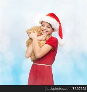 christmas, x-mas, winter, happiness concept - smiling girl in santa helper hat with teddy bear