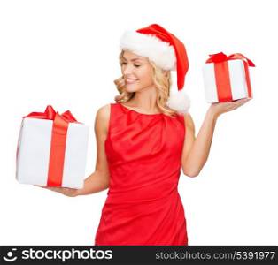 christmas, x-mas, winter, happiness concept - smiling woman in santa helper hat with small and big gift boxes