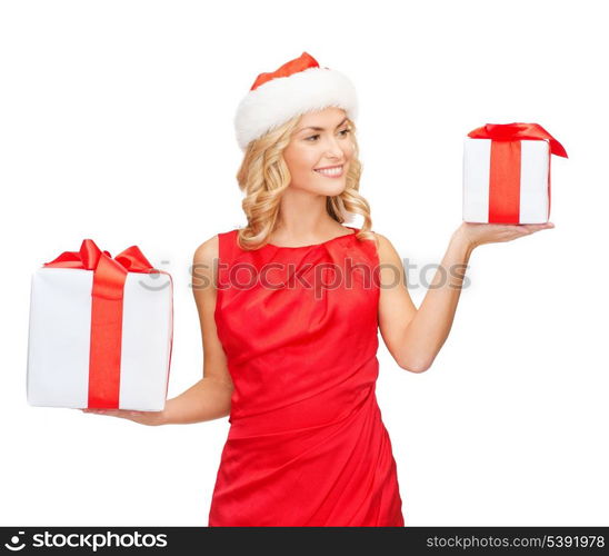 christmas, x-mas, winter, happiness concept - smiling woman in santa helper hat with small and big gift boxes