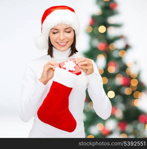 christmas, x-mas, winter, happiness concept - smiling woman in santa helper hat with small gift box and stocking