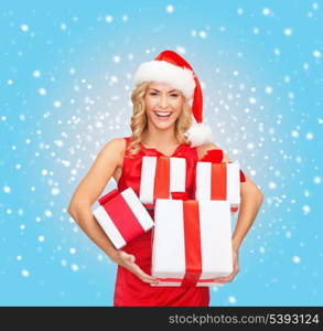 christmas, x-mas, winter, happiness concept - smiling woman in santa helper hat with many gift boxes