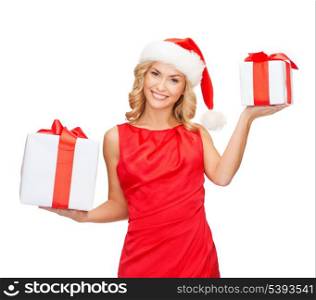 christmas, x-mas, winter, happiness concept - smiling woman in santa helper hat with small and big gift boxes