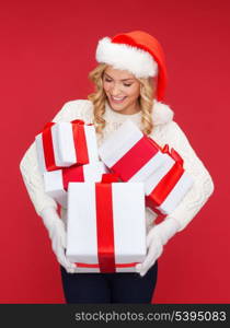 christmas, x-mas, winter, happiness concept - smiling woman in santa helper hat with many gift boxes