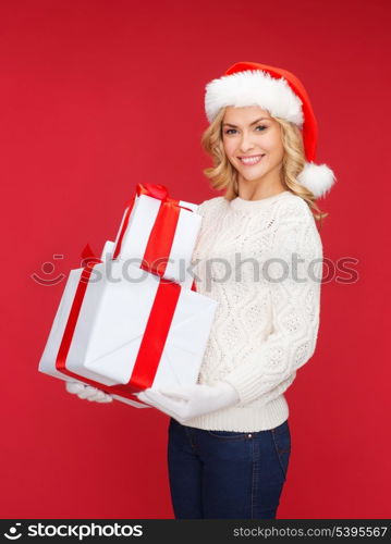 christmas, x-mas, winter, happiness concept - smiling woman in santa helper hat with many gift boxes