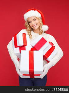 christmas, x-mas, winter, happiness concept - smiling woman in santa helper hat with many gift boxes