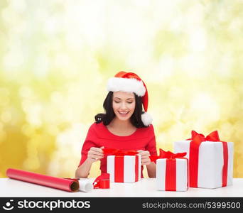 christmas, x-mas, winter, happiness concept - smiling woman in santa helper hat with many gift boxes