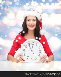 christmas, x-mas, winter, happiness concept - smiling woman in santa helper hat with clock showing 12