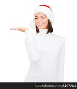 christmas, x-mas, winter, happiness concept - smiling woman in santa helper hat with something on palm