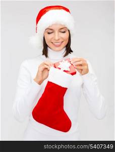 christmas, x-mas, winter, happiness concept - smiling woman in santa helper hat with small gift box and stocking