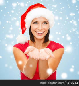 christmas, x-mas, winter, happiness concept - smiling woman in santa helper hat with something on palms