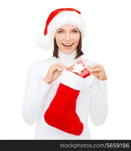 christmas, x-mas, winter, happiness concept - smiling woman in santa helper hat with small gift box and stocking