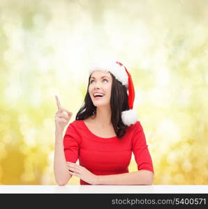 christmas, x-mas, winter, happiness concept - smiling woman in santa helper hat pointing to something