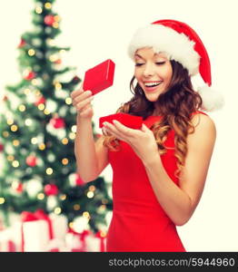 christmas, x-mas, winter, happiness concept - smiling woman in santa helper hat with gift box