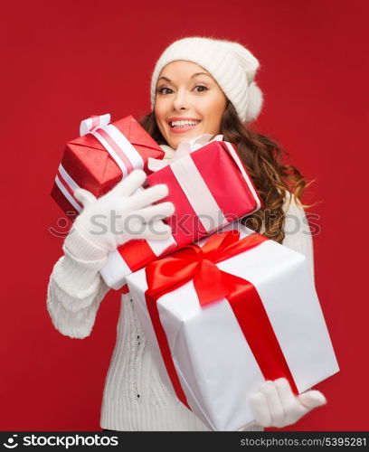 christmas, x-mas, winter, happiness concept - smiling woman in sweater and hat with many gift boxes