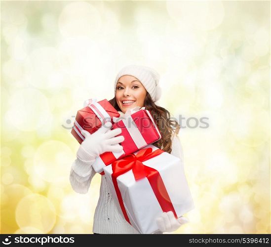 christmas, x-mas, winter, happiness concept - smiling woman in sweater and hat with many gift boxes