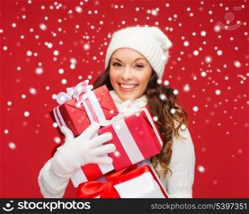 christmas, x-mas, winter, happiness concept - smiling woman in sweater and hat with many gift boxes