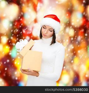 christmas, x-mas, winter, happiness concept - suspicious woman in santa helper hat with gift box