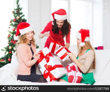 christmas, x-mas, winter, happiness concept - three smiling women in santa helper hats with many gift boxes