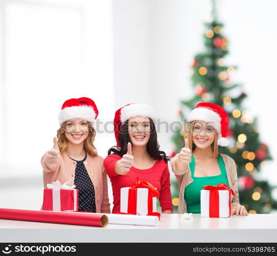 christmas, x-mas, winter, happiness concept - three smiling women in santa helper hats with gift boxes