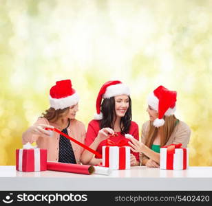 christmas, x-mas, winter, happiness concept - three smiling women in santa helper hats with gift boxes