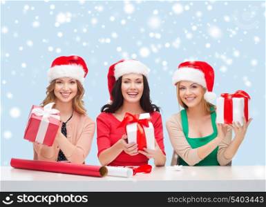 christmas, x-mas, winter, happiness concept - three smiling women in santa helper hats with gift boxes