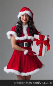 Christmas, x-mas, winter holidays concept - smiling woman in santa helper hat and dress with gift box. Christmas woman with gift box