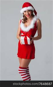 Christmas, x-mas, winter holidays concept - smiling woman in santa helper hat and dress with gift box. Christmas woman with gift box