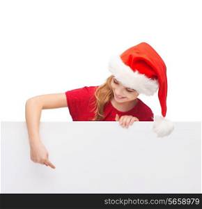 christmas, xmas, holidays and advertisement concept - happy girl child in santa helper hat pointing finger on blank white board