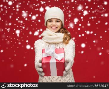 christmas, xmas, winter, happiness concept - smiling girl in hat, muffler and gloves with gift box