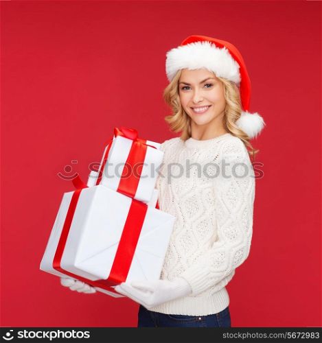 christmas, xmas, winter, happiness concept - smiling woman in santa helper hat with many gift boxes