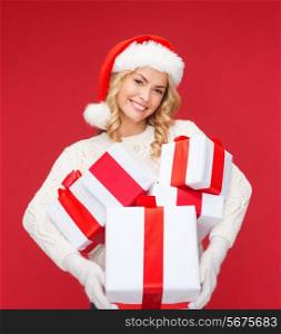 christmas, xmas, winter, happiness concept - smiling woman in santa helper hat with many gift boxes