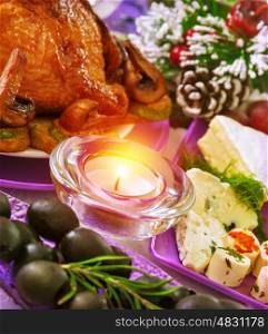 Christmastime banquet, festive table setting with bright candle light, New Year eve, tasty baked chicken, black olives, pine cone with snow decoration