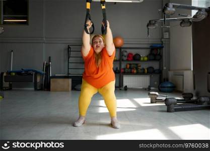 Chubby woman working in bodyweight training program using trx loops. Total resistance exercises for weight lost. Chubby woman working in bodyweight training program using trx loops