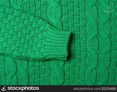 chunky knit of a sweater with green threads, full frame. Cozy and warm clothes