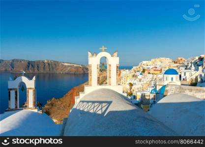 Church bell tower in Oia on Santorini Island.. View on Oia village with traditional blue and white houses.