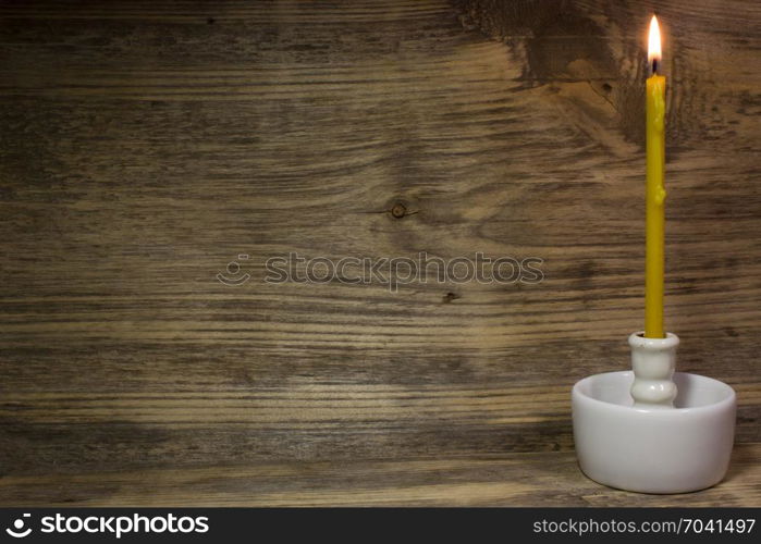 Church burning candle on wooden background