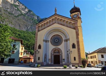 church in Mezzacorona village on sunny summer day with mountains in the background, Trentino, Italy