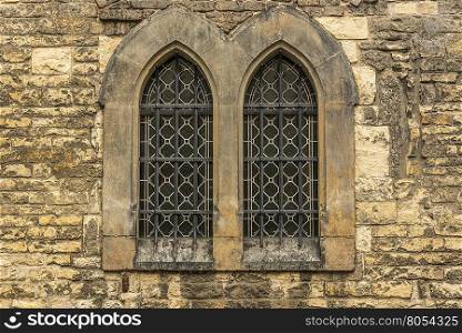 Church windows with bars - Architectural image with two windows from an old wall stoned church.