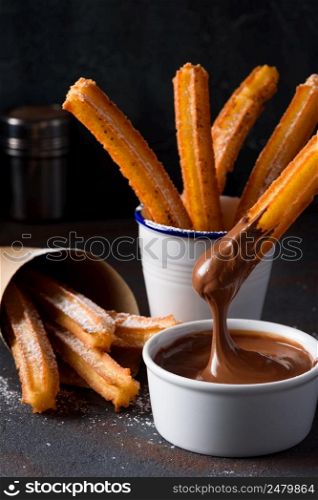 Churro with sugar powder and cinnamon in melted chocolate dip