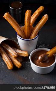 Churros with sugar and cinnamon in melted chocolate dip