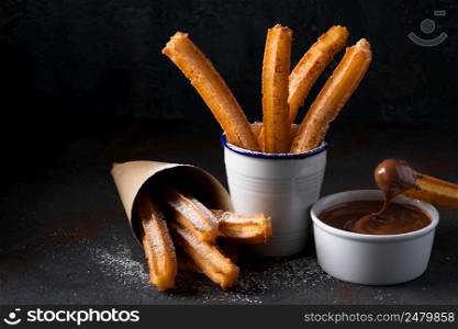 Churros with sugar powder and cinnamon in melted chocolate dip