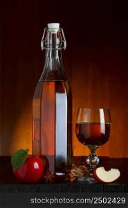 Cider bottle and glass with apple, cinnamon and anise star